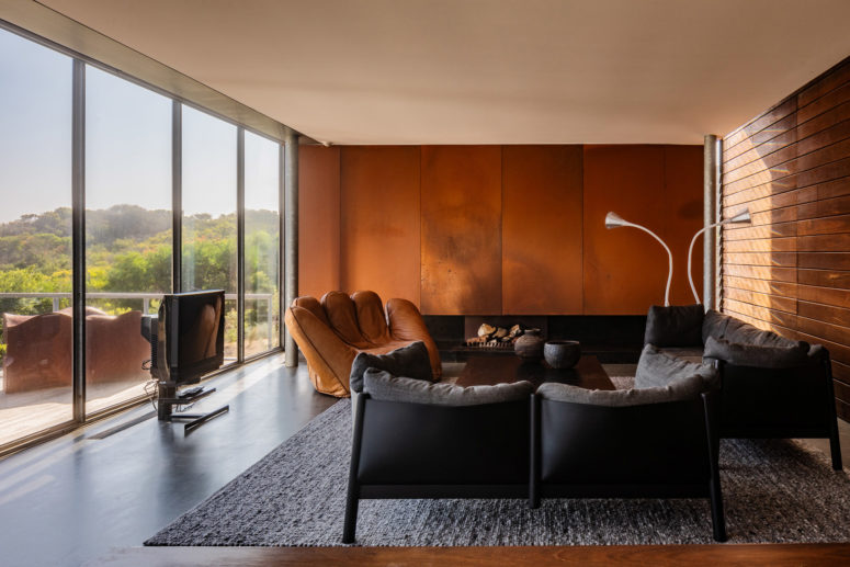 a built in fireplace is a nice focal point in this room Another living room is raised up, there's a built-in fireplace and the wall clad with copper, a leather hand chair and grey furniture
