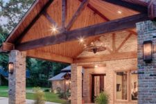 07 a stylish barndominium with brick pillars and a classic gabled roof with beams that feels very cozy and rustic