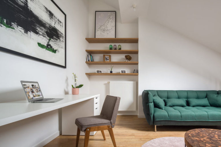 The home office space features a large white desk, a grey chair and some open shelves taking an awkward corner The home office space features a large white desk, a grey chair and some open shelves taking an awkward corner