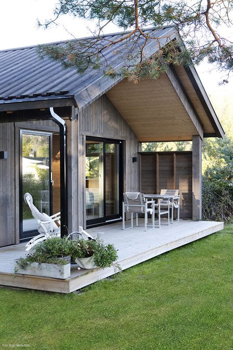 a backyard terrace of a barndominium under a gabled roof and with potted greenery on the deck