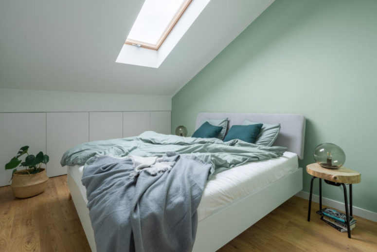 The bedroom is soothing, with a skylight, an upholstered bed and a larrge storage unit hidden behind sleke panels The bedroom is soothing, with a skylight, an upholstered bed and a larrge storage unit hidden behind sleke panels