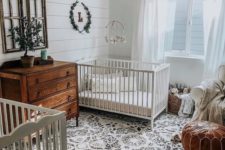 11 a farmhouse meets boho nursery with stained wooden furniture, a leather ottoman, a printed rug and greenery