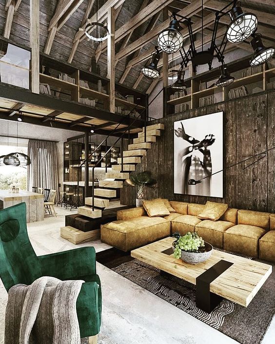a super edgy barndominium space with an emerald chair, a mustard sectional and statement artworks