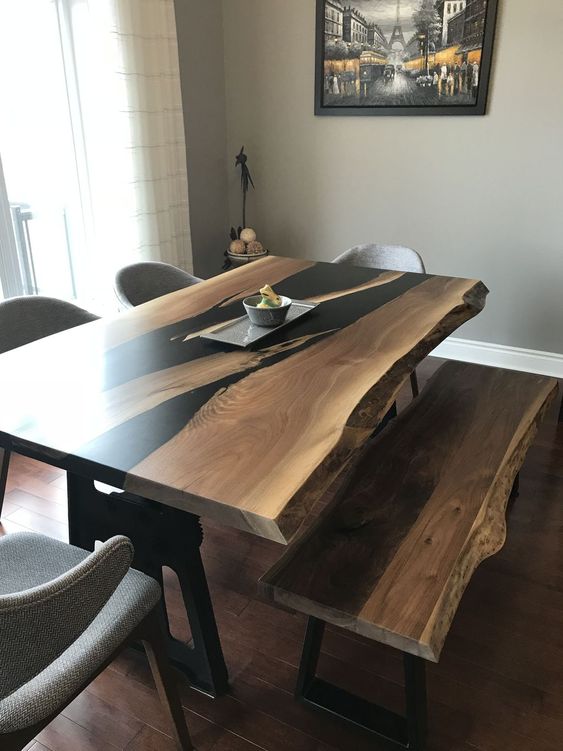 a sleek wooden dining table with black touches and a live edge plus a matching bench for a contemporary feel
