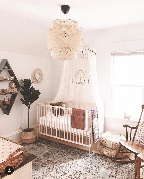 a farmhouse meets boho nursery with a statement wicker lamp, a printed rug, jute ottomans and a vintage rocker chairs