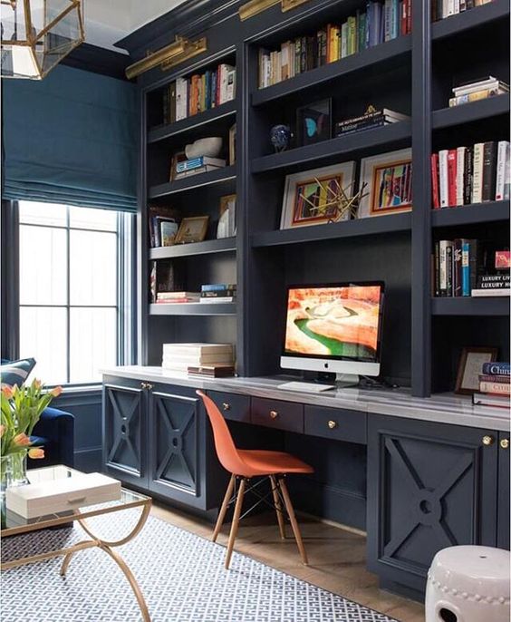 a rustic vintage home office with a dark blue wall unit and bright blue walls, a navy sofa and gold touches