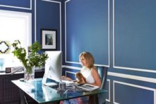 18 an elegant home office with navy and white walls, a dark blue patterned rug and a catchy trestle desk with a glass top