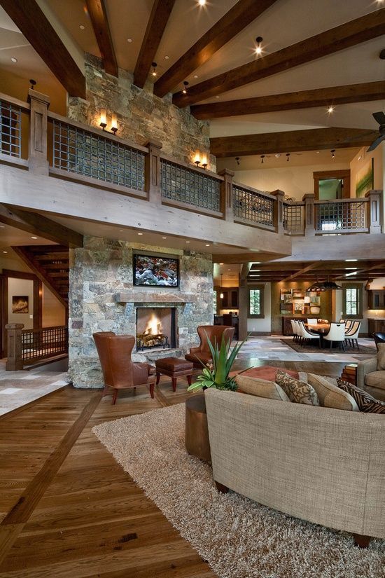 a cozy rustic barndominium space done with stone and wood, with warm-colored leather and a fireplace