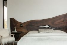 19 a modern bedroom with a rich stained live edge wooden headboard, an antler chandelier and a faux fur chair
