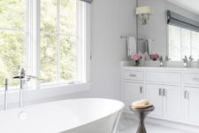 a chic and elegant bathroom with grey shades, a chic stand, a contemporary tub and a large mirror