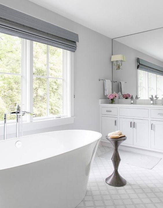 a chic and elegant bathroom with grey shades, a chic stand, a contemporary tub and a large mirror