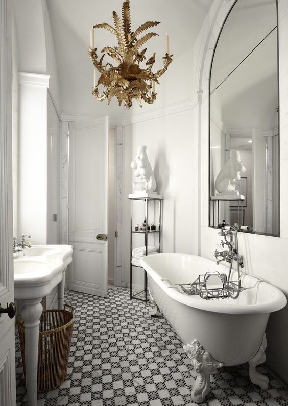 a chic vintage-inspired Parisian bathroom with a tiled floor, a gorgeous whimsy chandelier, a free-standing sink and a statement mirror