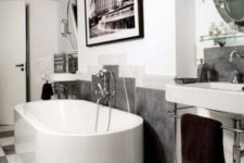 a contemporary monochromatic bathroom with a statement artwork, an oval tub, a free-standing sink and a checked floor