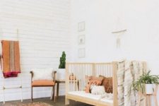 a free-spirited nursery with a boho rug, a wooden crib, potted greenery and touches of faux fur here and there