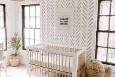 a gender neutral boho nursery with a wicker cactus, a Moroccan blanket rug, a folksy wallpaper wall, a wicker lamp and potted plants