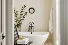 a neutral and warm-colored bathroom with shiplap, wood inspired tiles and a contemporary tub and black touches