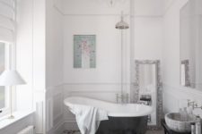 a stylish Parisian bathroom with a mosaic floor, elegant chandelier, a clawfoot tub, a side table and lamps