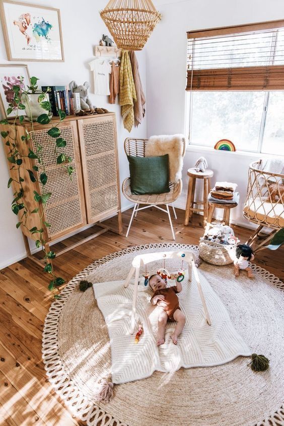 a warm-colored boho nursery with a cane dresser, a jute rug, a rattan bassinet, wooden and rattan furniture and greenery