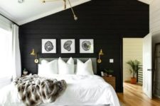 a welcoming rustic meets modern bedroom with a black shiplap wall, a neutral bed, gilded lighting fixtures and wooden nightstands