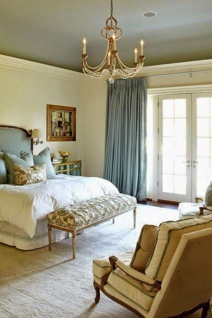 an elegant Parisian psace done with gold, beige, blues and a chic chandelier, an upholstered bench and refined furniture
