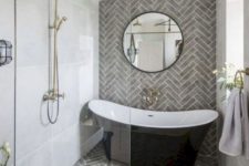 an elegant bathroom with grey tiles, a black tub, gilded touches, a black vanity and a round mirror looks super chic