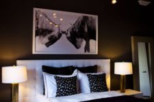 an elegant contemporary bedroom with a white upholstered bed, white nightstands, a chic chandelier and an artwork
