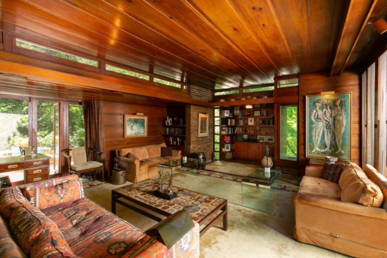 The living room is decorated with chic vintage and modern furniture, there's much warm colored wood and lots of windows The living room is decorated with chic vintage and modern furniture, there's much warm-colored wood and lots of windows