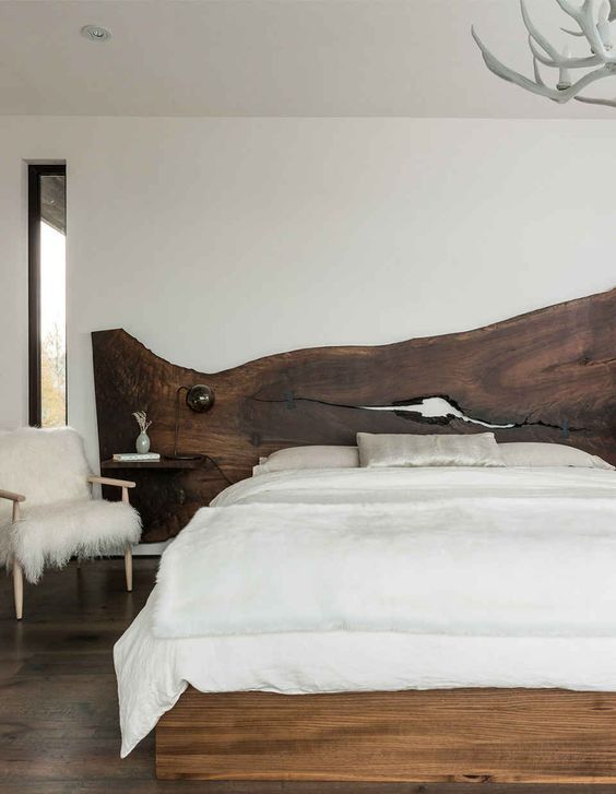 a dark stained live edge wooden headboard with imperfections and floating nightstands attached is a trendy idea