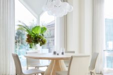 03 The dining space is done with a round table and curvy chairs plus a cluster of pendant lamps