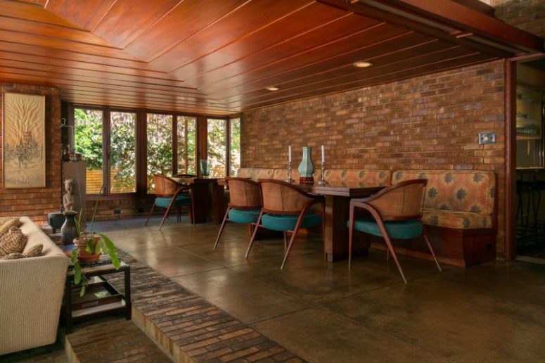 The dining zone is elevated, with teal and rattan chairs and a long upholstered bench along the wall