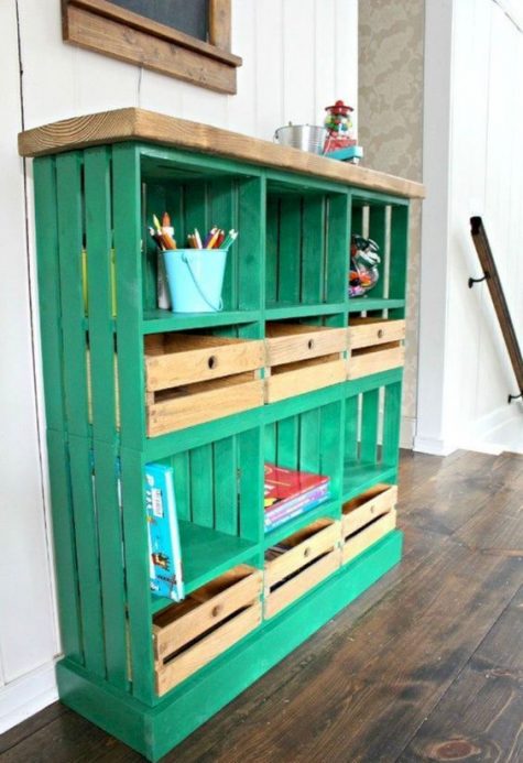 a bright emerald shelving unit built of crates and a wooden tabletop for a kids’ space