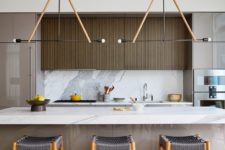 04 The kitchen is done with sleek cabinets, a marble backsplash and kitchen island and woven chairs