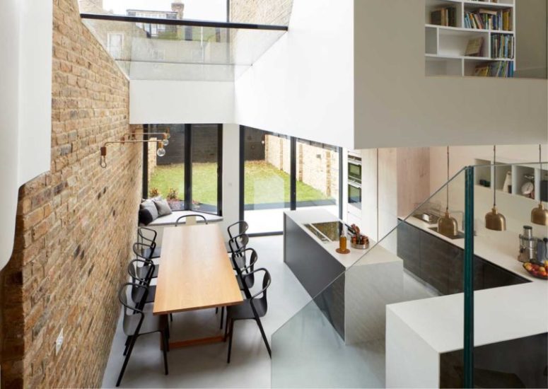 The kitchen is done with sleek dark cabinets, white countertops and there's a dining space with black chairs and a dining table The kitchen is done with sleek dark cabinets, white countertops and there's a dining space with black chairs and a dining table