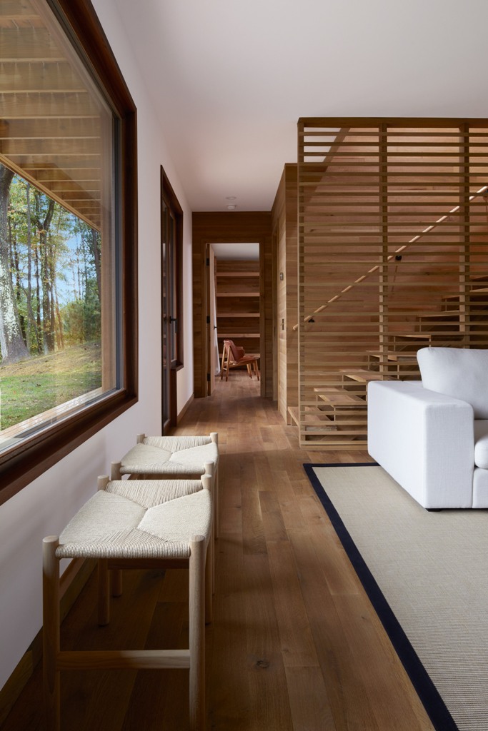 The spaces are done in neutrals, with lots of natural wood, chic mid-century furniture and a wooden slab screen to separate the staircase