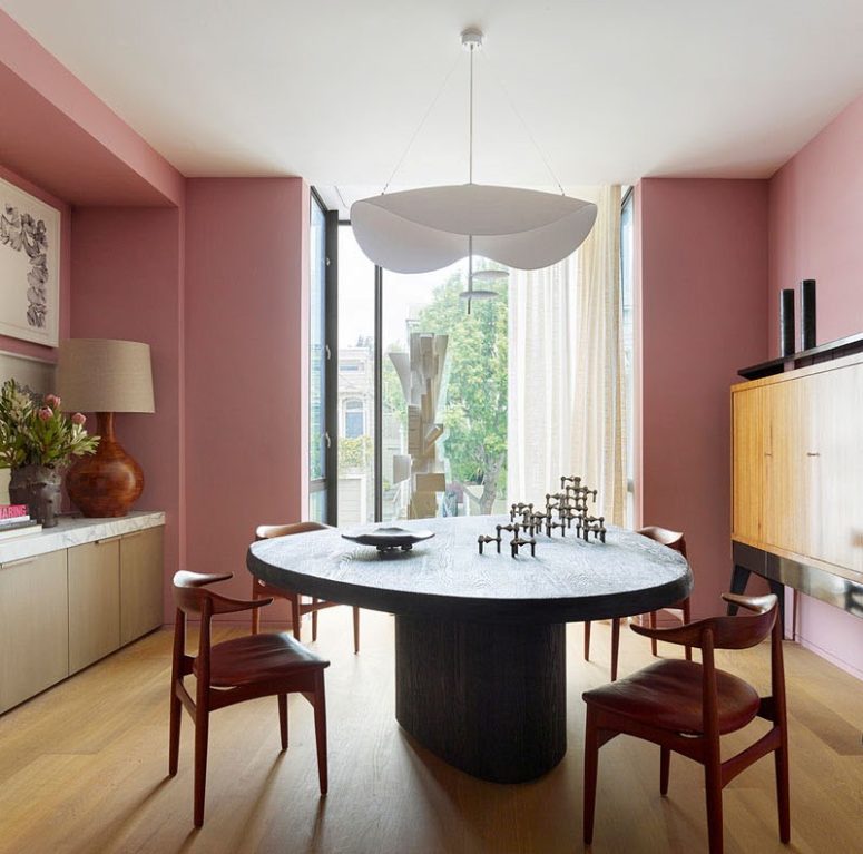 A dining room with a statement wooden dining table and a gorgeous chandelier features also pink walls A dining room with a statement wooden dining table and a gorgeous chandelier features also pink walls