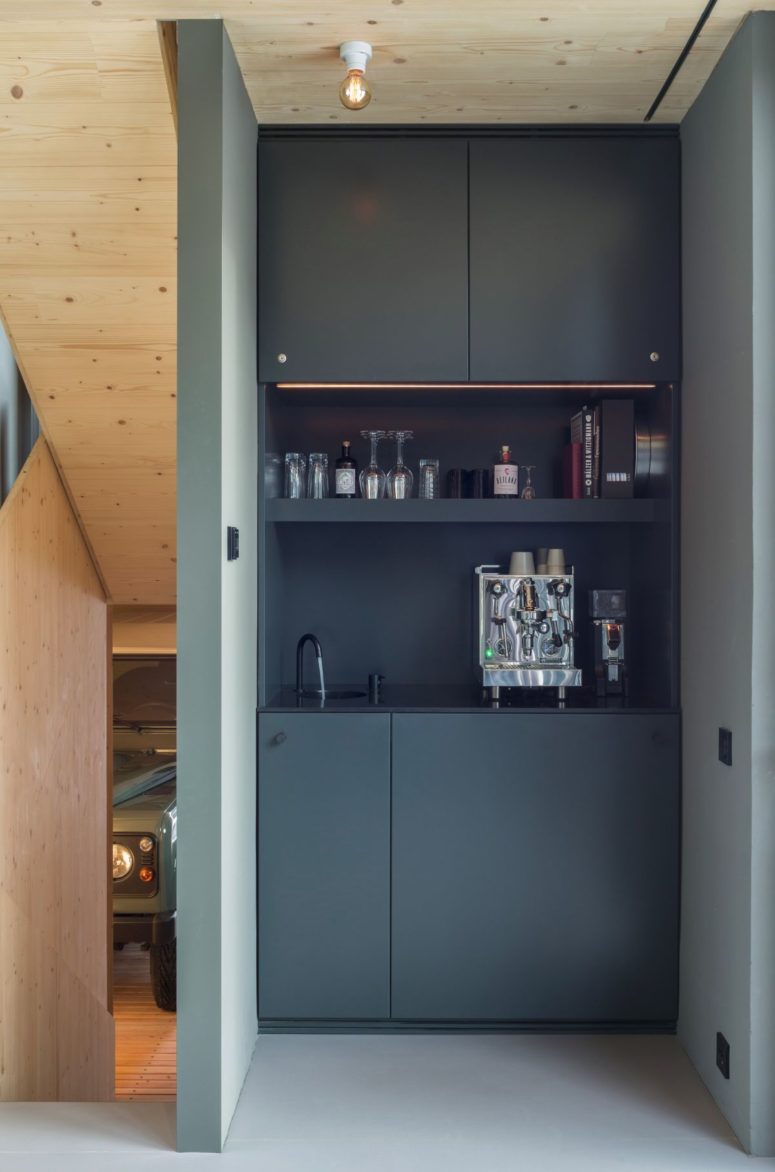 There's a tiny home bar with sleek dark cabinets, lights and a sink