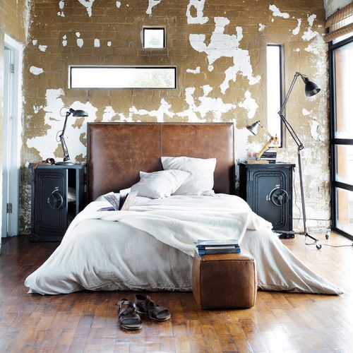 a sleek distressed leather headboard and a matching small ottoman bring color and texture to the room