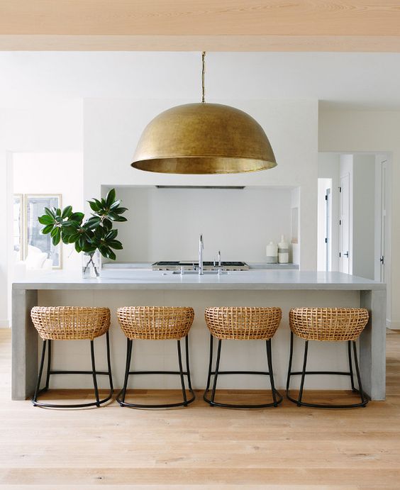 an oversized metal pendant lamp echoes with the rattan chairs and brings texture