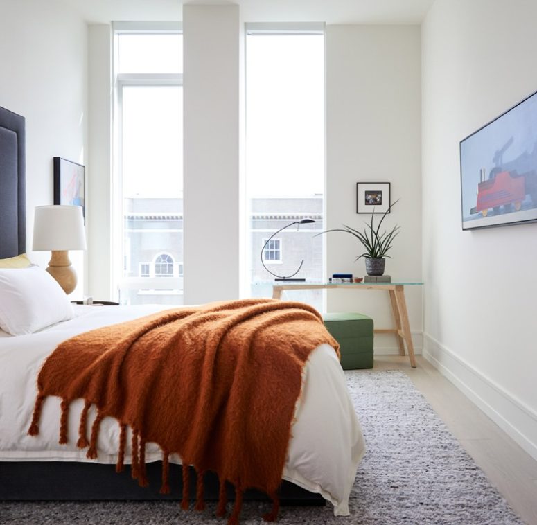 The guest bedroom is done with a dark bed, a glass table and catchy lamps and lots of natural light incoming