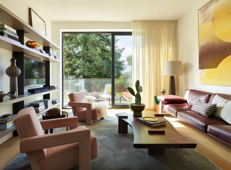 The living room is bright and bold, with pink chairs and a leather sofa plus an entrance to the terrace The living room is bright and bold, with pink chairs and a leather sofa plus an entrance to the terrace