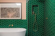 07 a bold bathroom with emerald tiles clad in a herringbone pattern and blush touches