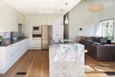 08 A large kitchen island with a grey stone countertop separates two zones from each other