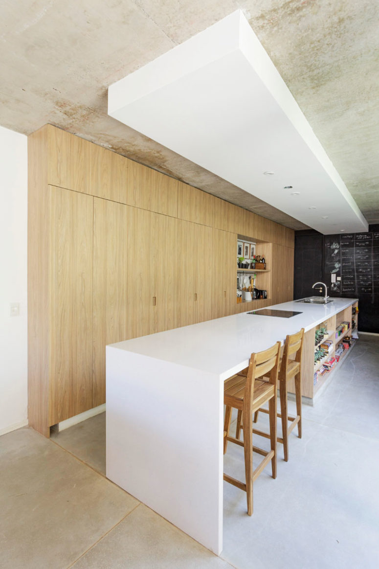 The kitchen is done with light colored wooden cabinets, a large and long white kitchen island with an eating space The kitchen is done with light-colored wooden cabinets, a large and long white kitchen island with an eating space