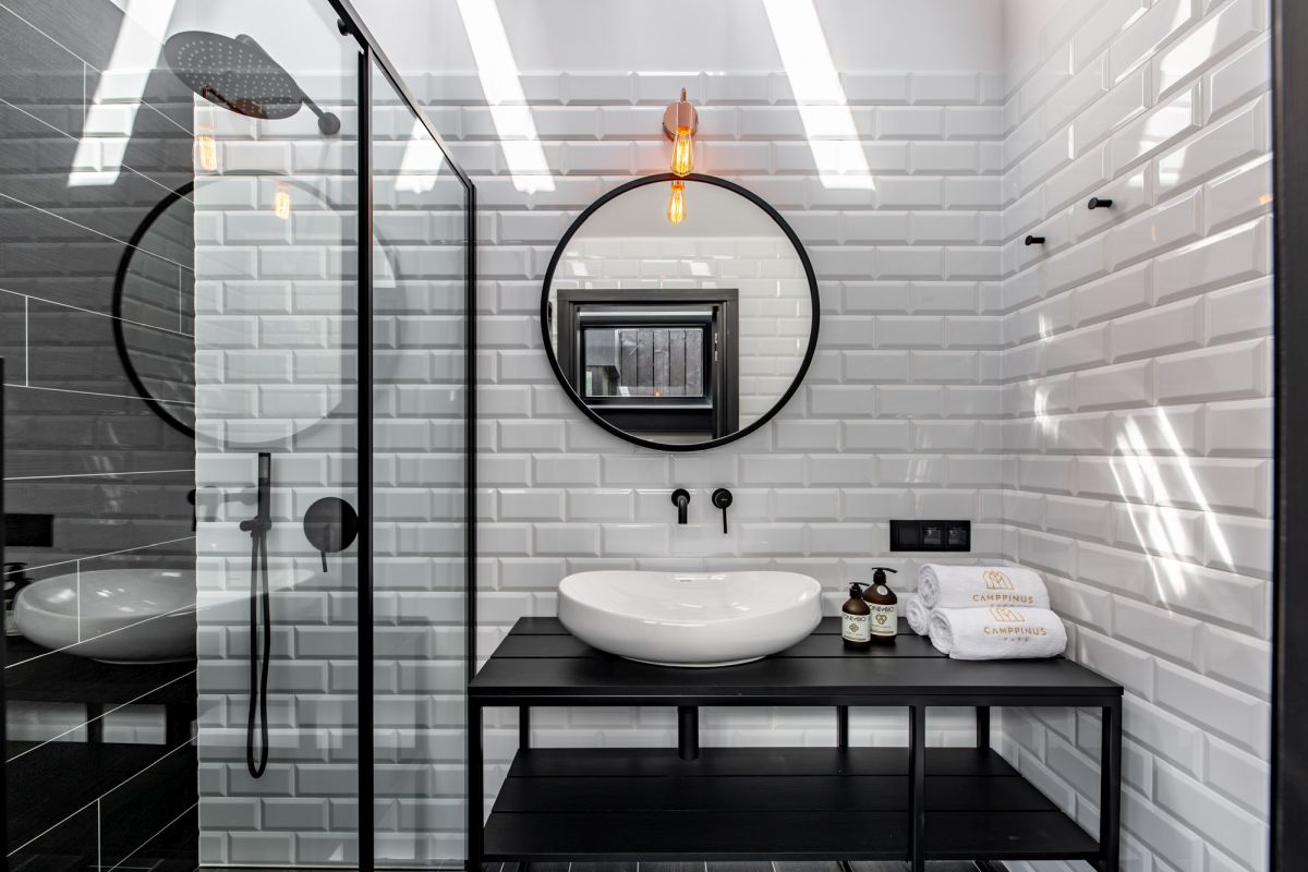 The bathroom is done with white subway tiles and black elements for a bold contrasting look