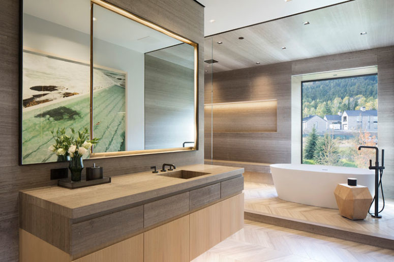 The contemporary bathroom is done with wood and a cool tub in front of the window