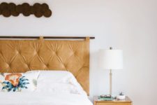 11 a hanging amber tufted leather headboard achoes with the nightstand and adds a warming up feel to the space