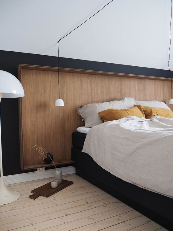 a sleek wooden headboard on a black wall makes a cozy and soothing statement and adds a calmign feeling to the room