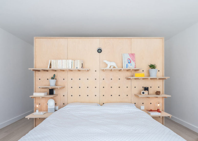 The master bedroom is done with a pegboard headboard for functionality and lots of shelves plus a bed