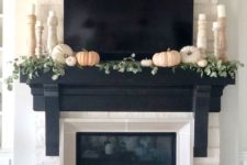 21 a fireplace decorated with muted and neutral pumpkins, foliage and candles in elegant wooden candleholders