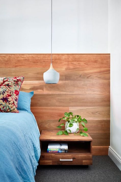 a sleek warm stained wooden headboard and a floating nightstand attached to it